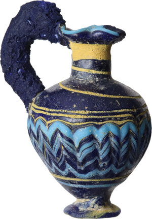 obverse: PUNIC MULTICOLOR OINOCHOE  Punic world, c. 6th century BC.  Small oinochoe in multicoloured glass paste. Three-lobed mouth, cylindrical neck, ovoid body, short trumpet foot. Decoration with horizontal bands and vertical blue and yellow spikes on a blue background.  Height (preserved): 81 mm