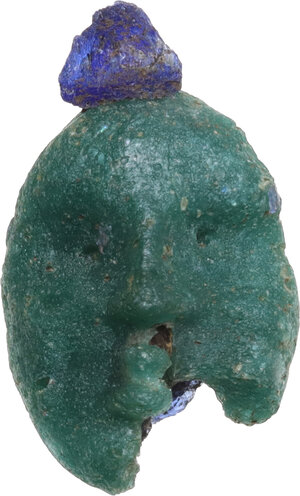 obverse: PHOENICIAN GLASS PASTE HEAD  Punic culture, c. 5th century BC.  Green and blue glass paste pendant, depicting a face with hair gathered in the back.  Dimensions: 21 x 12 mm