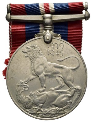 reverse: Medaglie Estere – Regno Unito – Giorgio VI (1936-1952) – WW2 – 1939-45. La medaglia di guerra 1939-1945 è una medaglia di campagna istituita dal Regno Unito il 16 agosto 1945, per l assegnazione ai cittadini del Commonwealth britannico che avevano prestato servizio a tempo pieno nelle forze armate o nella marina mercantile per almeno 28 giorni tra 3 settembre 1939 e 2 settembre 1945. La durata della Seconda guerra mondiale in Europa andò dal 3 settembre 1939 all 8 maggio 1945, mentre nel Pacific Theatre continuò fino al 2 settembre 1945. La War Medal 1939-1945 fu istituita dal Regno Unito il 16 agosto 1945 e fu insignita a tutto il personale a tempo pieno delle forze armate e della marina mercantile per aver prestato servizio per 28 giorni, indipendentemente dal luogo in cui prestava servizio, tra il 3 settembre 1939 e il 2 settembre 1945 compreso, per l intera durata della Seconda guerra mondiale. Nella Marina mercantile, i 28 giorni dovevano essere serviti ovunque in mare. Il requisito di qualificazione per l assegnazione della medaglia di guerra 1939-1945 al personale militare a tempo pieno era di 28 giorni di servizio, ovunque resi. Il servizio di qualificazione nella Marina mercantile era di 28 giorni di servizio ovunque in mare durante il periodo di qualificazione. Anche i cittadini stranieri incaricati o arruolati nelle forze britanniche, che non avevano ricevuto un premio simile alla medaglia di guerra 1939-1945 dai propri governi, potevano qualificarsi per l assegnazione di questa medaglia. I membri retribuiti a tempo pieno delle forze coloniali e di altre forze militari appositamente approvate, della polizia militarizzata o degli organismi civili militarizzati che erano idonei a qualificarsi per le stelle della campagna, potevano anche qualificarsi entro 28 giorni di servizio durante il periodo di qualificazione previsto per la forza interessati, come segue: Polizia armata di Aden dal 3 febbraio 1939 al 2 settembre 1945. British Honduras Defence Force dal 3 settembre 1939 al 3 dicembre 1939. Polizia della Guyana britannica, esclusi coloro che hanno cessato di appartenere alla Forza per motivi diversi da morte, cattiva salute o età, dal 3 settembre 1939 al 14 luglio 1945. Banda militare della Guyana britannica dal 29 aprile 1942 all 8 maggio 1945. Forza di polizia di Cipro impiegata in servizio militare a tempo pieno dal 10 giugno 1940 al 12 giugno 1941. Forza volontaria di Cipro dal 2 giugno 1941 al 2 settembre 1945. Gambia Police Force dal 5 luglio 1940 al 17 agosto 1940. Trasporto per acque interne dell esercito gambiano sulla SS Munshi dal 21 luglio 1942 al 31 maggio 1944. Gibraltar Defence Force dal 3 settembre 1939 al 2 settembre 1945. Polizia di sicurezza di Gibilterra dal 3 settembre 1939 al 2 settembre 1945. Forza di polizia della Nigeria dal 23 luglio 1940 all 8 maggio 1945. Forza di polizia palestinese dal 27 maggio 1942 all 8 maggio 1945. Sudan Defence Force per il servizio permanente a tempo pieno ovunque nel Sudan dal 3 settembre 1939 all 8 maggio 1945. Trinidad Police Force dal 3 settembre 1939 al 2 settembre 1945. Zanzibar Police Force dal 3 settembre 1939 al 2 settembre 1945. La qualifica per le categorie appositamente approvate di civili in uniforme che potevano qualificarsi per le stelle della campagna era di 28 giorni di servizio nell area di un comando operativo dell esercito all estero, o all estero da o fuori dal paese di residenza in aree non operative soggette a nemico attacco aereo o minacciato da vicino. Il servizio nel Regno Unito o nel territorio di residenza, diverso da un area operativa dell esercito, non era una qualifica per queste categorie. La medaglia è stata assegnata al personale il cui periodo di servizio richiesto è stato interrotto prematuramente per morte, disabilità dovuta al servizio o alla cattura come prigioniero di guerra e il cui servizio li ha qualificati per una delle stelle della campagna della Seconda guerra mondiale. Anche il personale che aveva ricevuto una delle stelle per un servizio inferiore a 28 giorni ricevette la medaglia di guerra 1939-1945. La medaglia di guerra 1939-1945 è un disco di 36 millimetri di diametro. La bretella a barra dritta non girevole è attaccata alla medaglia con un attacco ad artiglio a punta singola e un perno attraverso il bordo superiore della medaglia. Le medaglie di emissione britannica erano coniate in cupronichel, mentre quelle assegnate in Canada (circa 700.000) erano coniate in argento. La medaglia viene talvolta erroneamente chiamata 