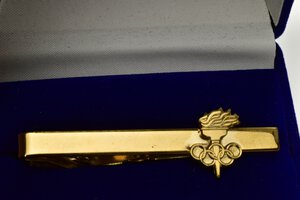 obverse: Fermacravatte con logo olimpico databile al periodo 2010-2020. Realizzato in bronzo dorato (AE) (11x58mm, 7.1gr.). Conservazione FDC. 