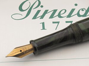 reverse: PINEIDER Juliet.  -Penna Stilografica- Corpo in ebanite di colore nero/verde sfumato con finiture in metallo dorato. Clip con con pietra verde a taglio Cabochon. Ricarica a cartuccia/converter. Pennino M in oro giallo 18kt.  Penna nuova, mai inchiostrata né provata, venduta in scatola originale e garanzia. Alcuni  difetti sulla scatola.. n.d.