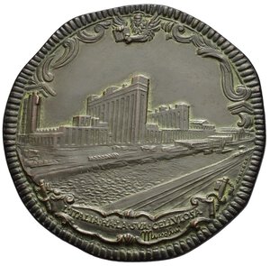 reverse: Medaglie Italiane – Regno d’Italia – Vittorio Emanuele III (1900-1945) - Ventennio Fascista – Industria Tessile SNIA Torviscosa (Udine)  – Non Comune (NC). Medaglia statica dalla particolare forma stondata realizzata nel 1940 per ricordare la società SNIA. Al dritto in alto: leone di San Marco tra volute Veduta prospettica degli Stabilimenti Torviscosa sotto in cartiglio legato a fasci obliqui: L ITALIA HA LA SUA CELLULOSA = MUSSOLINI in basso a dx: JOHNSON. Al rovescio TORRE DI ZVINO 21 SETT. XVI = TORVISCOSA 21 SETT. XVIII entro piante di canna e in cartiglio: stemma turrito della SNIA sotto a sx: ME sotto, entro nastro: AB. _ AVTARCHIA • IMPE _ RIVM. Realizzata in bronzo patinato (AE) (Ø 59.5mm, 64.3g). Conservazione SPL. Opus Emilio Monti. In astuccio d’epoca marchiato Monnaie de Paris. Riferimenti Casolari XVIII-56. Torviscosa è un comune italiano di 2 589 abitanti del Friuli-Venezia Giulia. Il centro storico del capoluogo è stato costruito tra il 1938 e il 1960 dalla SNIA Viscosa, che si era insediata in questo territorio con un grande stabilimento industriale per la produzione di cellulosa per fibre tessili. Torviscosa è pertanto una città aziendale. Alcune delle caratteristiche estetiche e in particolare la piazza principale (piazza del Popolo) la fanno inoltre rientrare anche tra le città di fondazione di epoca fascista. Nel 1937, la SNIA Viscosa comincia ad acquistare vaste quantità di terreno nei dintorni di Torre di Zuino con l obiettivo di iniziare una coltivazione su larga scala di Arundo donax, la comune canna gentile, da cui ricavare la cellulosa necessaria alla propria produzione di fibre tessili. I primi terreni acquistati, circa 1400 ettari, sono quelli della Società Anonima Bonifiche del Friuli e della Società Anonima Bonifiche Torre di Zuino. Sono terreni già bonificati e coltivati ormai da alcuni anni: le coltivazioni esistenti vengono perciò eliminate per piantare i rizomi della canna gentile. Nel corso del 1938 la SNIA acquista anche il tenimento di Malisana (circa 550 ettari, di proprietà di Vittorio Marchioro) e entra in possesso del tenimento di Torre di Zuino (circa 990 ettari), la cui compravendita verrà di fatto formalizzata solo nel 1940. Su questo terreno, formalmente di proprietà della S.a.s. Tenimento Torre di Zuino, la SNIA Viscosa costruisce lo stabilimento industriale destinato alla lavorazione delle materie prime per l estrazione di cellulosa. Lo stabilimento viene inaugurato il 21 settembre 1938 alla presenza di Mussolini. Nel 1940 la SNIA Viscosa chiede e ottiene l elevazione di Torre di Zuino, fino ad allora frazione di San Giorgio di Nogaro, a comune autonomo con il nome di Torviscosa. 