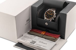 reverse: # IWC Pilot’s Chronograph. Movimento a carica automatica. Referenza IW377730. Seriale 727XXXXX. Cassa in acciaio con diametro da 43mm.  Dial nero con indici a numeri arabi arancioni. Funzione cronografo a 3 contatori con secondi in piccolo al 9. Ore, minuti e secondi del cronografo al centro. Sfere luminescenti. Bracciale in pelle scamosciata con chiusura deployante in acciaio originale. Vetro zaffiro. Fondello a pressione. Anno 2023. Orologio NUOVO, venduto con tutto il corredo completo composto da scatola, controscatola, libretto d istruzioni, panno per la pulizia e garanzia. Eccezionalmente custodito, mai indossato. Perfettamente funzionante.  A completare il corredo, viene venduto anche un cinturino originale marcato “AS Roma” con i colori classici della famosa squadra di calcio Italiana. 