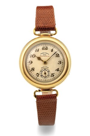 obverse: Angora Watch Bird, anni 30 Cassa rotonda in oro 18k, lunetta con profilo scannellato svitabile per regolazione orologio, estraibile tramite cerniera. Quadrante color crema con finitura grené, numeri arabi applicati. Movimento a carica manuale. Cinturino in pelle. Dimensioni: 32 mm.  Note: Cassa impermeabile realizzata da François Borgel.