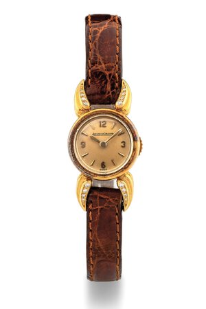 obverse: Jaeger-LeCoultre Mini Duoplan, anni 50 Cassa rotonda in oro rosa 18k, anse a fiamma settate diamanti. Quadrante color crema, indici e numeri arabi applicati. Movimento a carica manuale. Cinturino in pelle. Dimensioni: 16 mm.